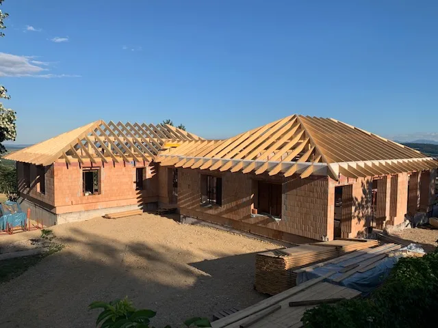 Rohbau mit fertig aufgestelltem Walmdach-Dachstuhl im Abendlicht