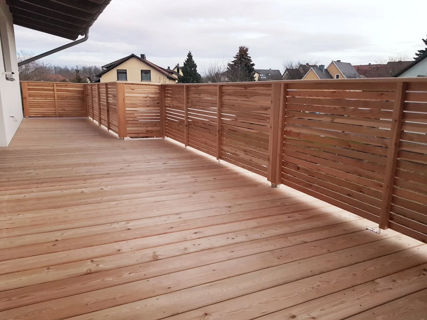 Fertige Holzterrasse mit waagrechtem Lattensichtschutz