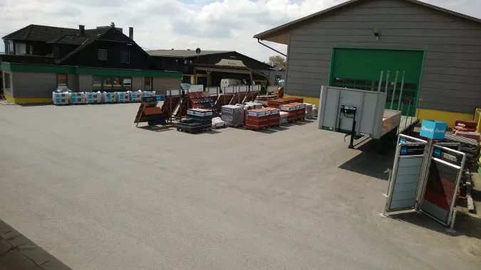 Betriebshof mit Materiallager, Dachziegelmustern und grünen Hallentoren